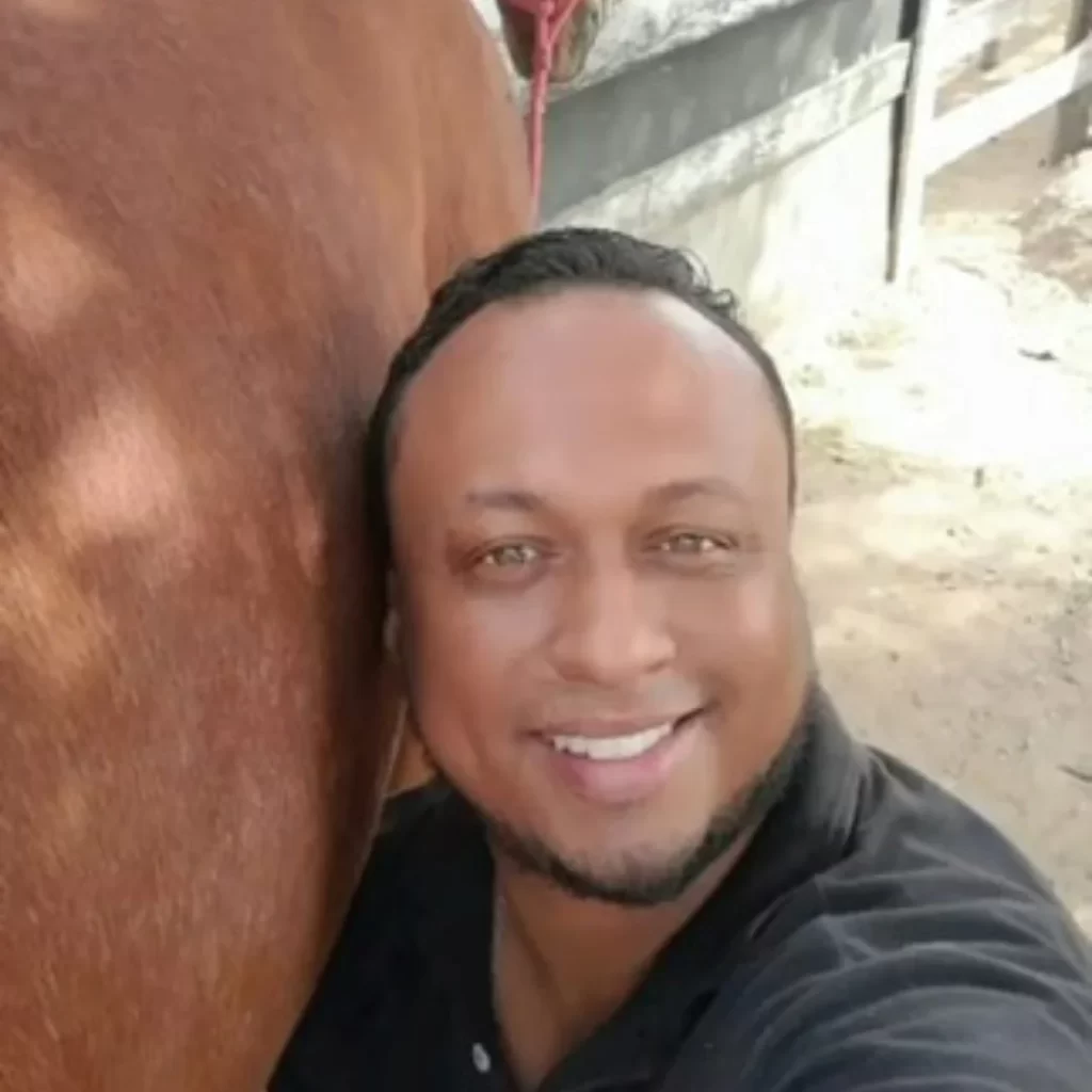 Anderson Pereira de Abreu sorrindo ao lado de cavalo durante aula de fisiatria equina no Instituto VetSociety